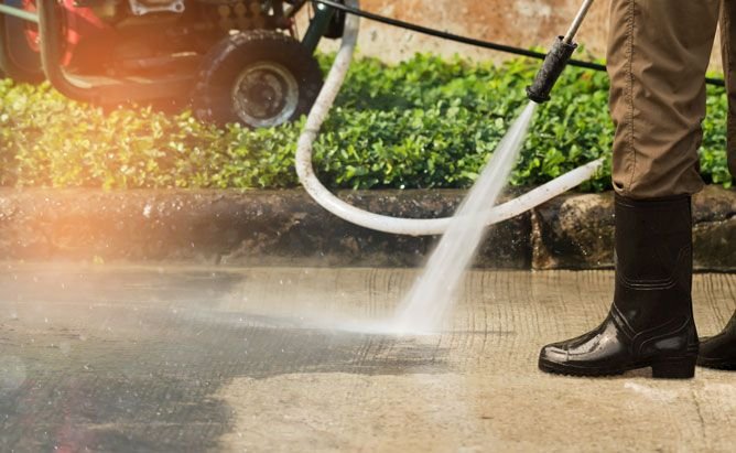Worker cleaning driveway with gasoline high pressure washer 
